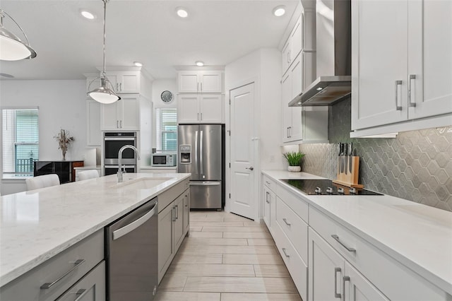 kitchen with wall chimney range hood, decorative backsplash, plenty of natural light, stainless steel appliances, and a sink