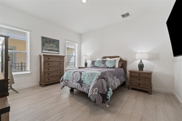 bedroom with light wood-type flooring, visible vents, and baseboards