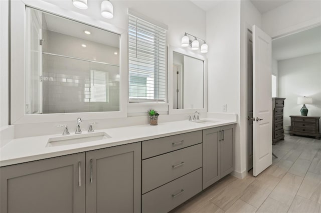 full bath with double vanity, tiled shower, and a sink