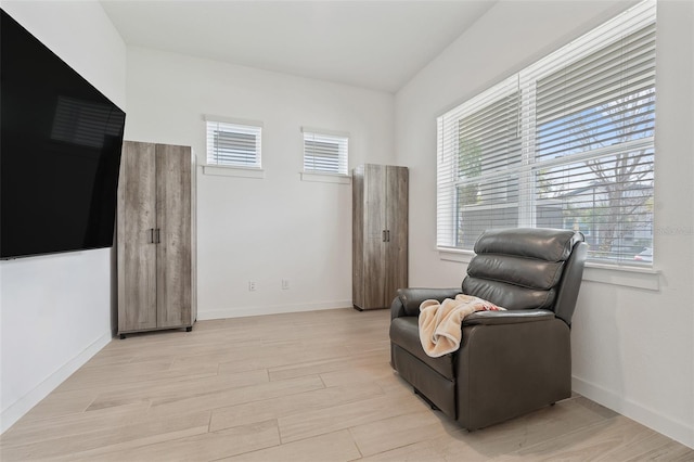 sitting room with baseboards, light wood-style floors, and a healthy amount of sunlight