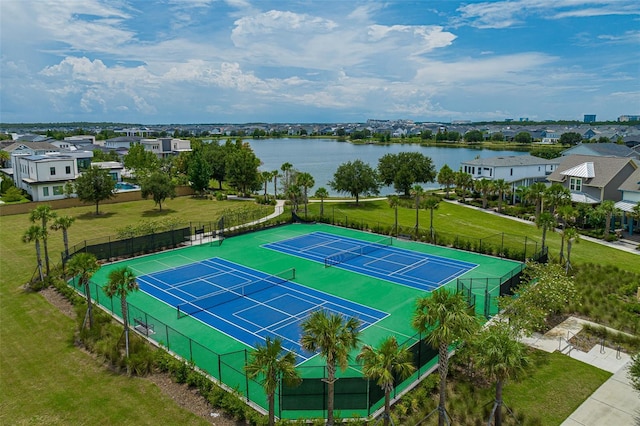 view of sport court featuring a yard, a water view, and fence