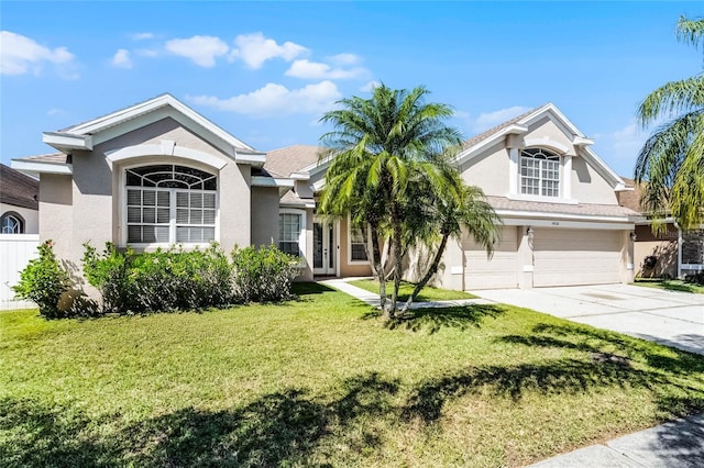 view of front facade featuring stucco siding, a garage, concrete driveway, and a front lawn