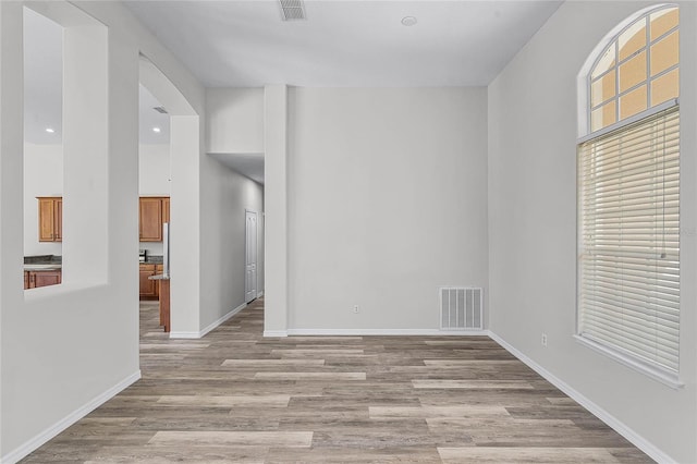 empty room featuring light wood-type flooring, visible vents, and plenty of natural light