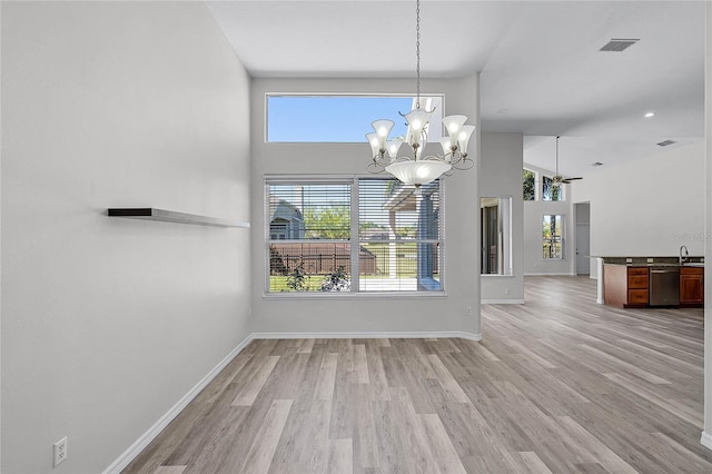 unfurnished dining area with a sink, baseboards, light wood-style floors, and a high ceiling