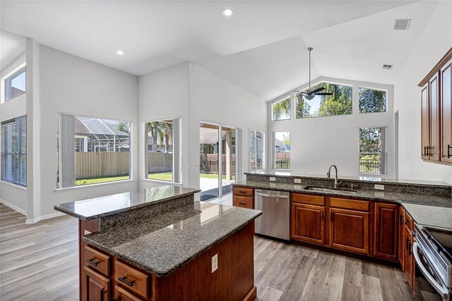 kitchen featuring dark stone countertops, stainless steel appliances, light wood-style floors, and a sink