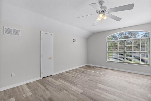 empty room with visible vents, baseboards, light wood-style flooring, and vaulted ceiling