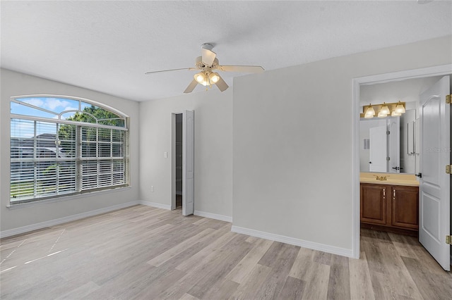 unfurnished bedroom featuring a sink, baseboards, and light wood-style floors