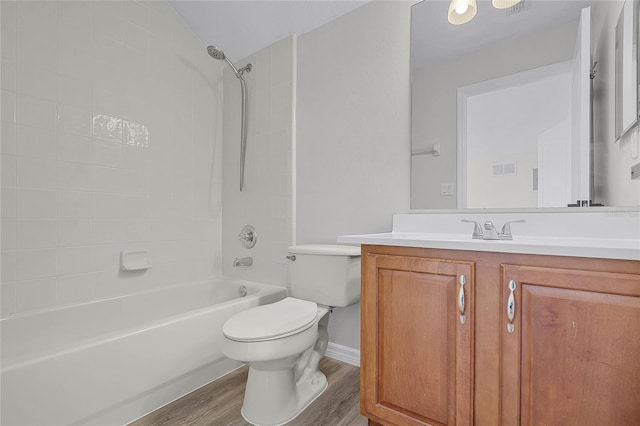 bathroom featuring vanity, wood finished floors, baseboards, toilet, and shower / bathtub combination