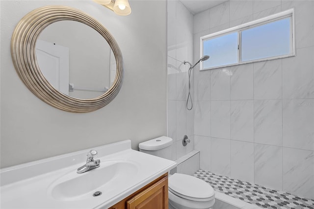 full bath featuring toilet, vanity, and a tile shower