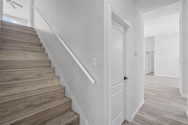 stairway with ceiling fan, baseboards, and wood finished floors