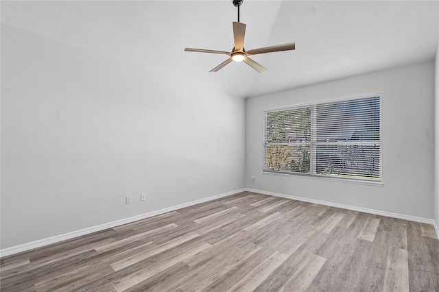 spare room with baseboards, a textured ceiling, wood finished floors, and a ceiling fan