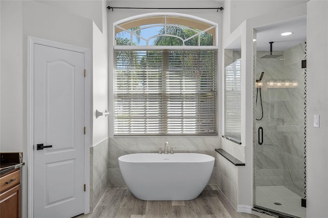 full bath featuring a wealth of natural light, a freestanding bath, tile walls, and a shower stall