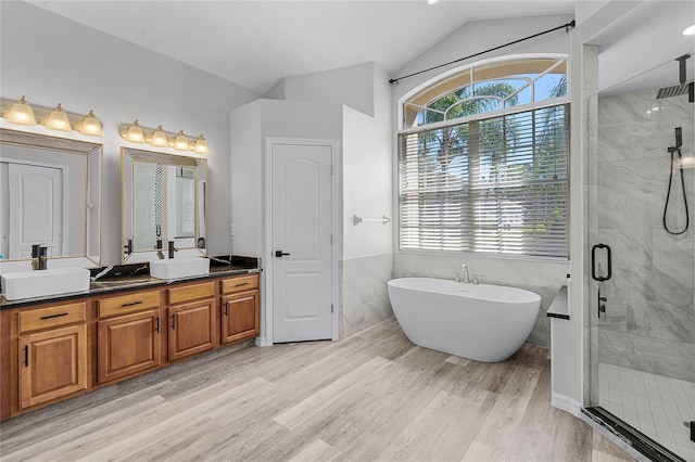 bathroom featuring a shower stall, wood finished floors, double vanity, and a sink