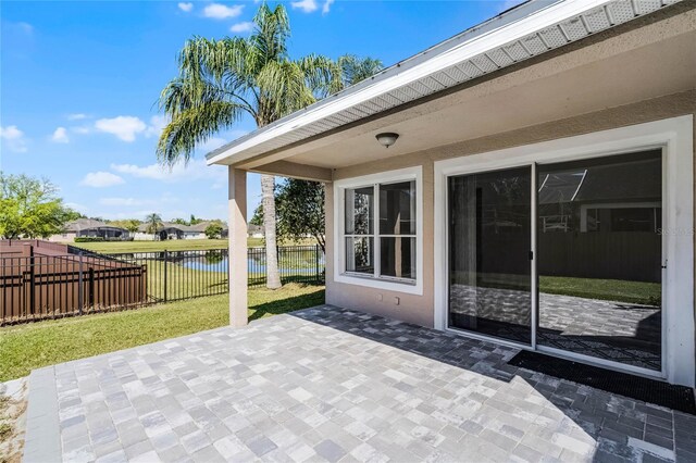 view of patio featuring a water view and fence