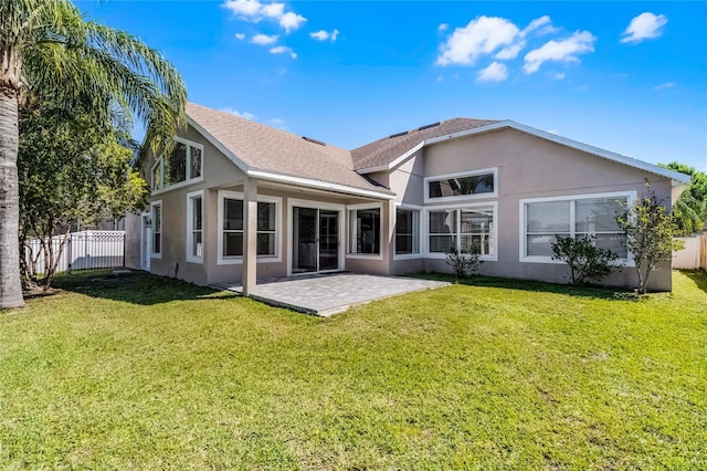 back of property featuring fence, roof with shingles, stucco siding, a patio area, and a lawn