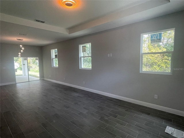 unfurnished room with visible vents, baseboards, plenty of natural light, and dark wood finished floors