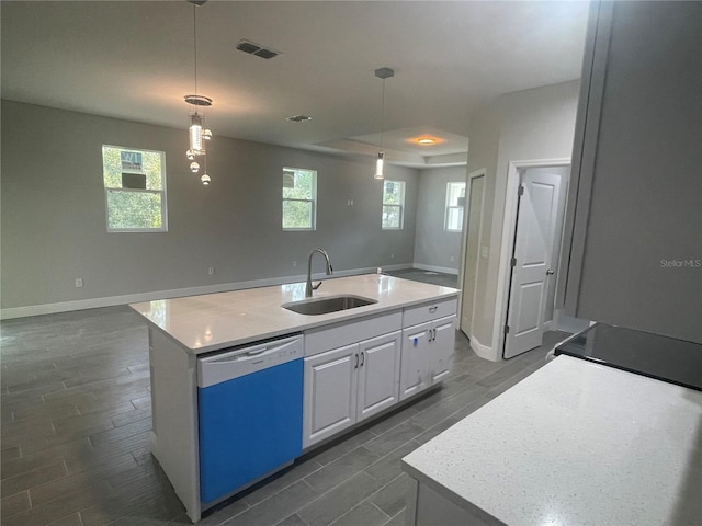 kitchen featuring visible vents, an island with sink, a sink, white cabinets, and dishwashing machine