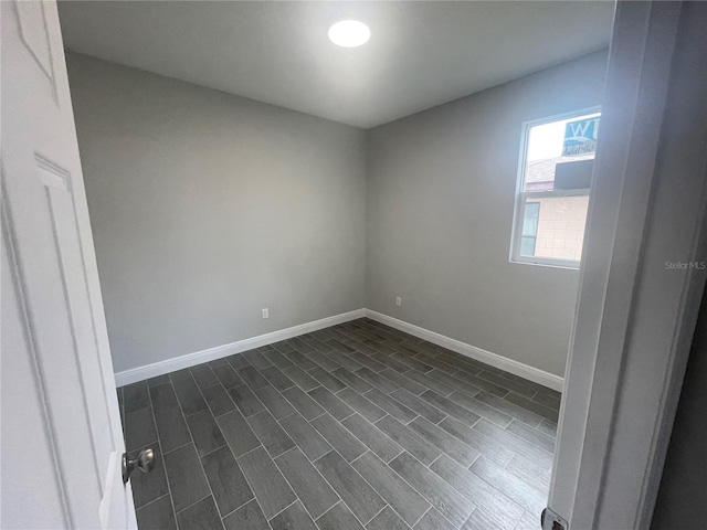 spare room featuring dark wood-style floors and baseboards