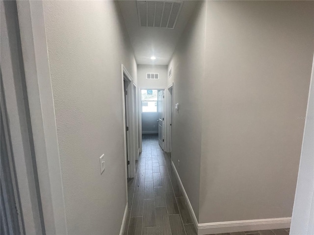 hallway featuring wood finish floors, visible vents, and baseboards