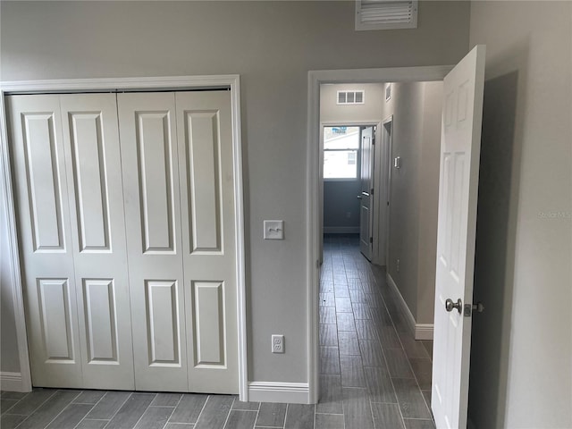 corridor featuring visible vents, baseboards, and wood tiled floor