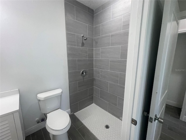 bathroom featuring baseboards, toilet, and a stall shower