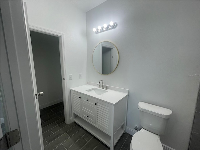 bathroom featuring toilet, vanity, and baseboards