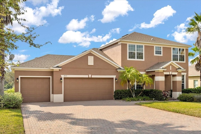 view of front of property with stucco siding, decorative driveway, a garage, and roof with shingles