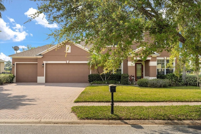 view of front of home featuring stucco siding, decorative driveway, a garage, and a front lawn