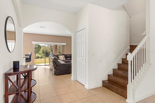 stairway with tile patterned floors, arched walkways, and baseboards