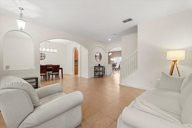 living area with visible vents, arched walkways, light tile patterned floors, baseboards, and stairs