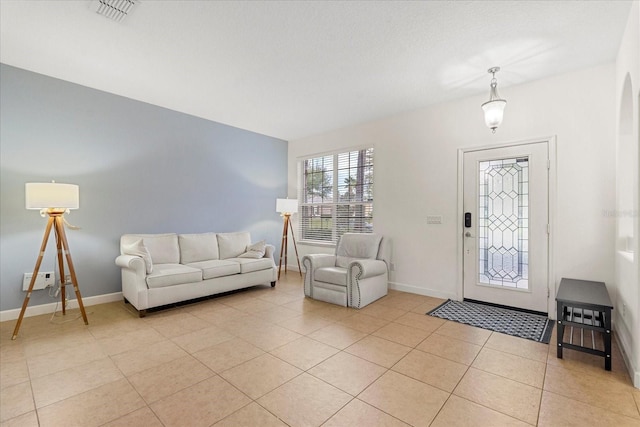 living room with light tile patterned floors, visible vents, baseboards, and arched walkways