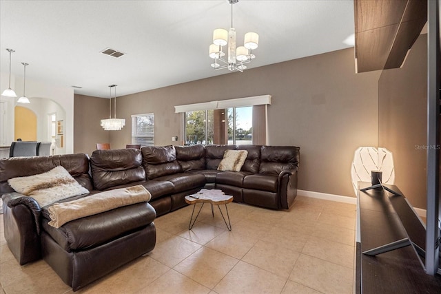 living area featuring a notable chandelier, arched walkways, visible vents, and baseboards