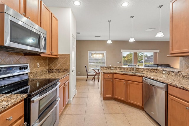 kitchen featuring a sink, appliances with stainless steel finishes, light tile patterned flooring, decorative backsplash, and light stone countertops