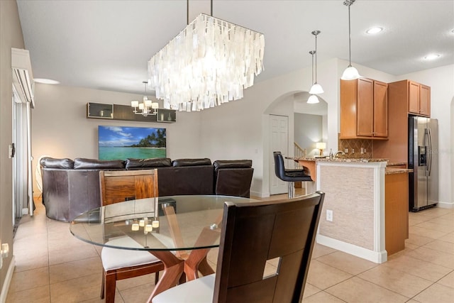 dining space with light tile patterned floors, recessed lighting, arched walkways, and an inviting chandelier