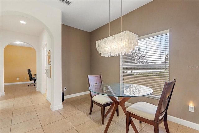 dining room featuring light tile patterned floors, visible vents, arched walkways, and baseboards