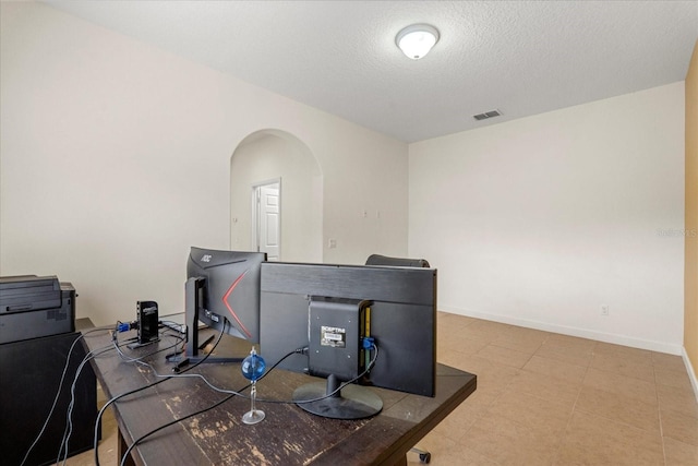 home office with visible vents, arched walkways, a textured ceiling, and baseboards