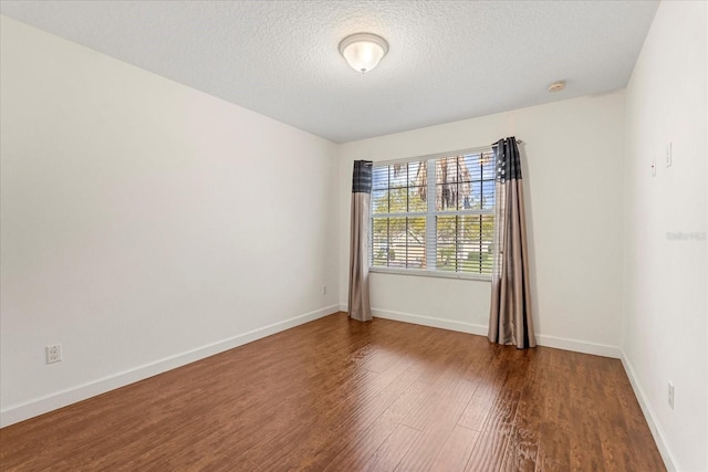 unfurnished room featuring wood finished floors, baseboards, and a textured ceiling