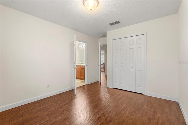 unfurnished bedroom with visible vents, baseboards, wood finished floors, a closet, and a textured ceiling