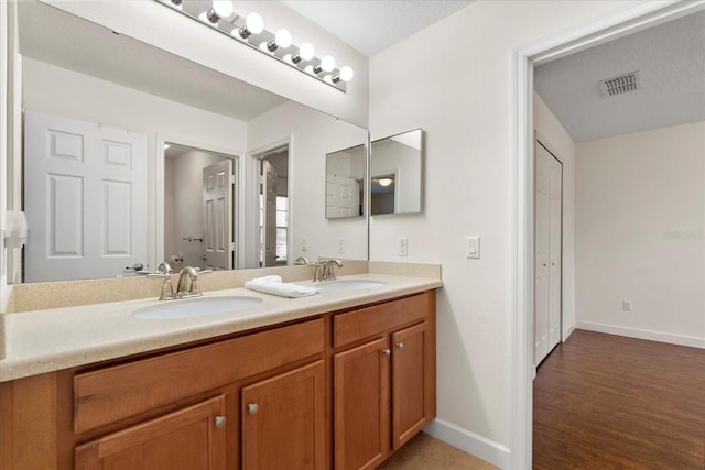 full bathroom featuring a sink, visible vents, baseboards, and double vanity