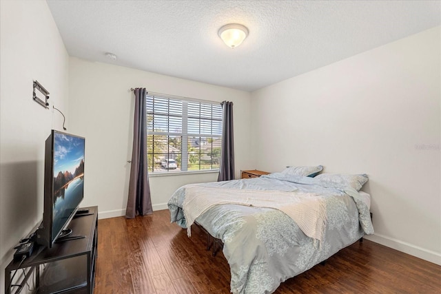 bedroom featuring baseboards, a textured ceiling, and wood finished floors