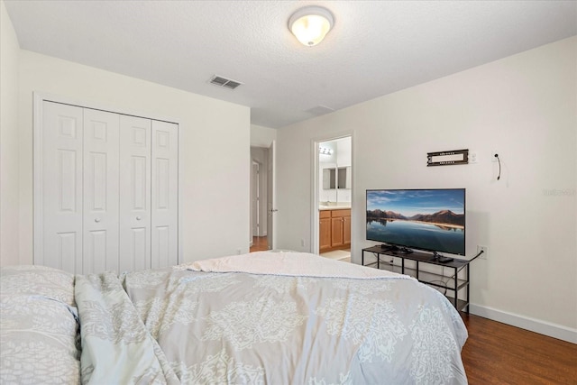 bedroom featuring visible vents, baseboards, wood finished floors, a closet, and a textured ceiling