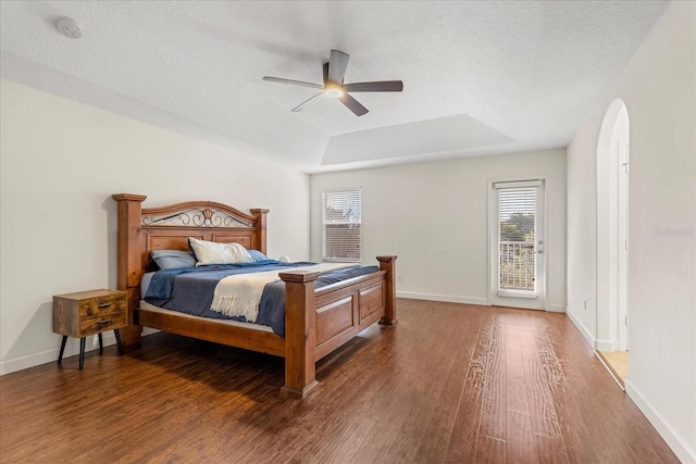 bedroom featuring baseboards, a raised ceiling, and wood finished floors