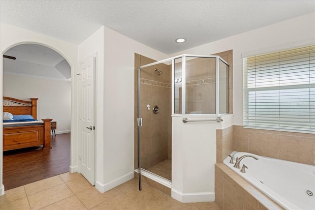 ensuite bathroom with ensuite bath, tile patterned flooring, a shower stall, a textured ceiling, and a garden tub