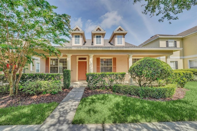 view of front of house with a front yard, covered porch, and stucco siding