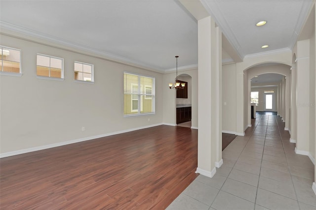 interior space with light wood-type flooring, arched walkways, baseboards, and ornamental molding