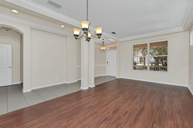 unfurnished room with visible vents, ornamental molding, wood finished floors, arched walkways, and baseboards