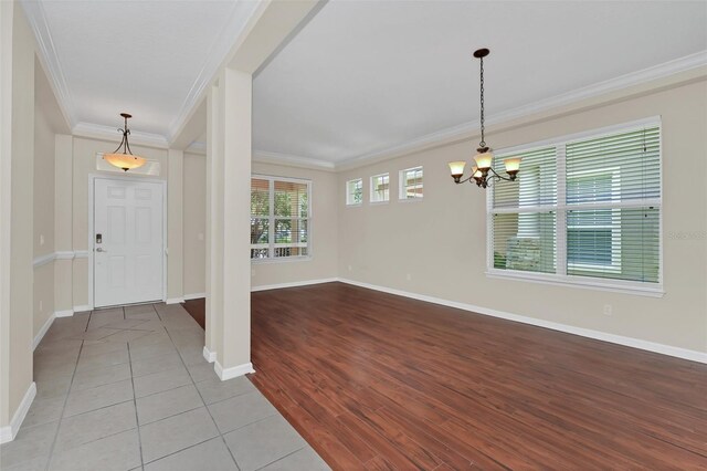 entrance foyer with an inviting chandelier, wood finished floors, crown molding, and baseboards