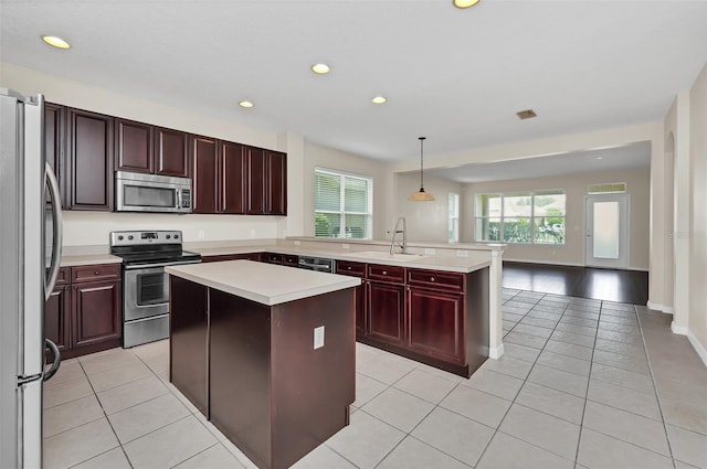 kitchen featuring a sink, a kitchen island, stainless steel appliances, a peninsula, and light countertops