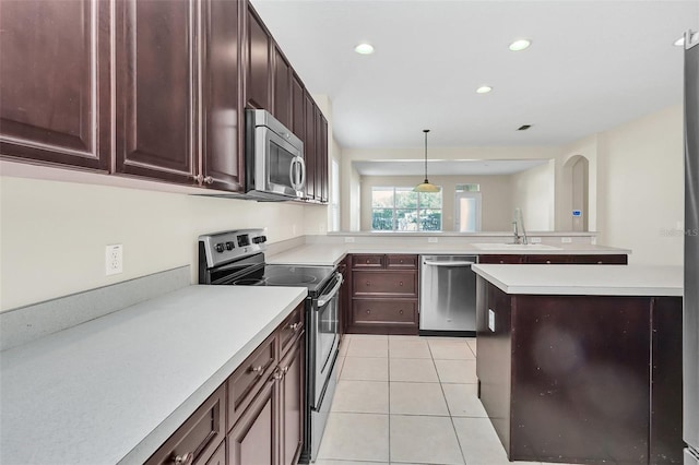 kitchen with a sink, appliances with stainless steel finishes, a peninsula, light countertops, and light tile patterned floors