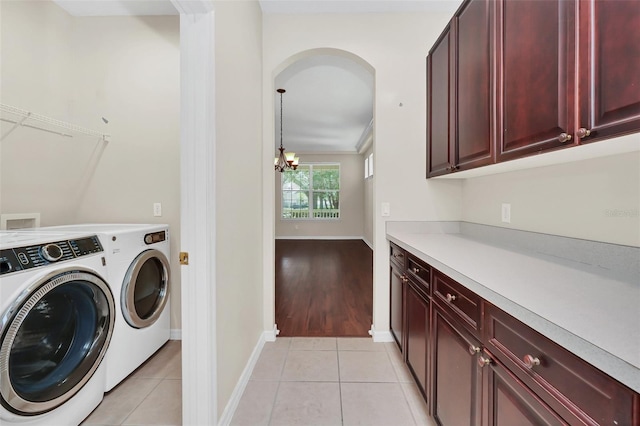 laundry room with baseboards, a chandelier, light tile patterned floors, cabinet space, and separate washer and dryer